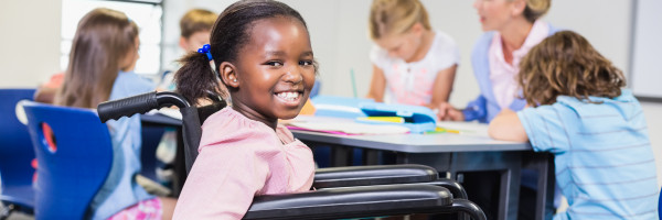 young girl on a wheel chair smiling at the camera