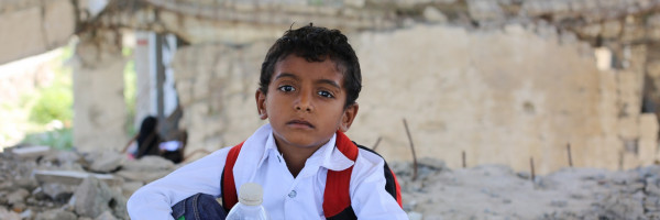 sad Yemeni child facing his school destroyed