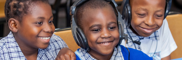 crianças sorrindo enquanto ouvem em fones de ouvido