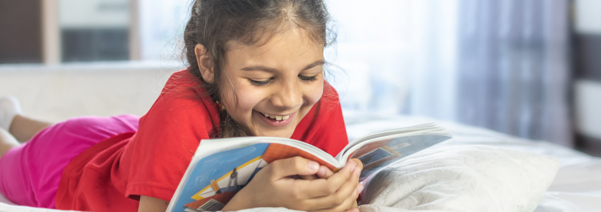 A girl is reading a book and smiling. 
